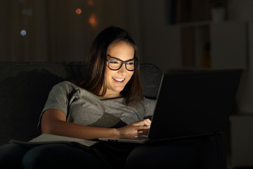 Woman wearing eyeglasses using a laptop in the night