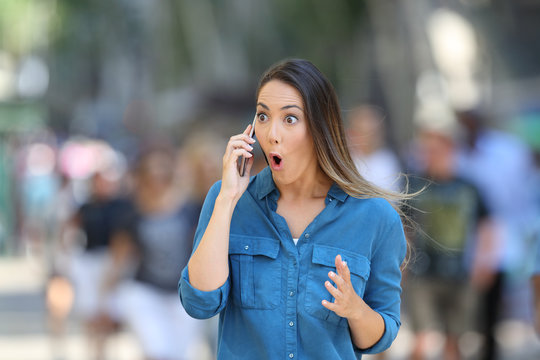 Amazed woman receiving news on phone