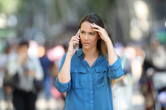 Worried woman talks on the phone in the street