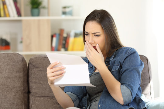 Sad woman reading bad news in a paper letter