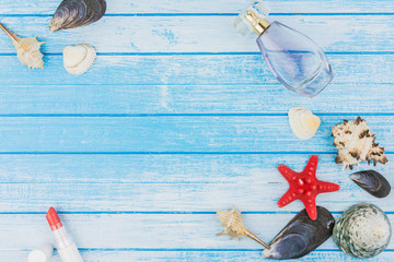 Fototapeta na wymiar Sea Shells Decorations Parfume Bottle Lip Stick And Sea Star On Blue And White Painted Wood Background High Contrast Summer Concept