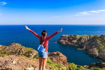 Tourist woman with backpack on Cap de Creus, natural park. Eastern point of Spain, Girona province, Catalonia. Famous tourist destination in Costa Brava. Sunny summer day with blue sky and clouds © oleg_p_100