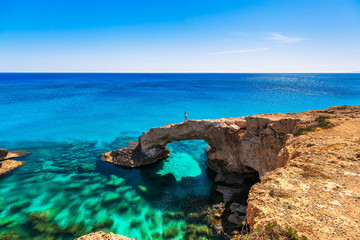 Frau auf dem schönen natürlichen Felsbogen in der Nähe von Ayia Napa, Cavo Greco und Protaras auf der Insel Zypern, Mittelmeer. Legendäre Brückenliebhaber. Erstaunliches blaugrünes Meer und sonniger Tag.