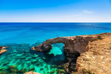 Selbstklebende Fototapete Zypern Frau auf dem schönen natürlichen Felsbogen in der Nähe von Ayia Napa, Cavo Greco und Protaras auf der Insel Zypern, Mittelmeer. Legendäre Brückenliebhaber. Erstaunliches blaugrünes Meer und sonniger Tag.