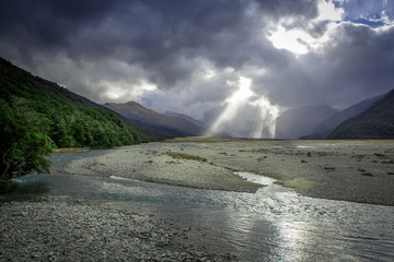 The sunlight shining through the clouds during a rainstorm casts a dramatic scene over the valley...