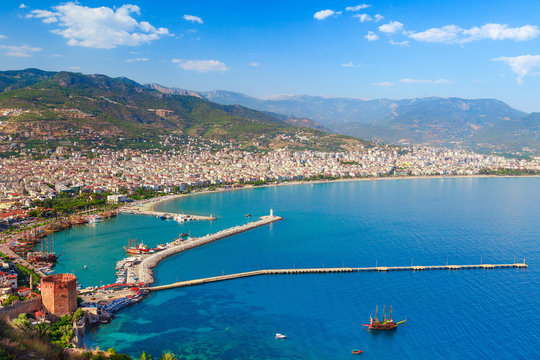 Landscape of Alanya with marina and Kizil Kule red tower in Antalya district, Turkey, Asia. Famous tourist destination with high mountains. Summer bright day and sea shore