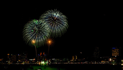 Many flashing fireworks with night cityscape background celebrate New Year.