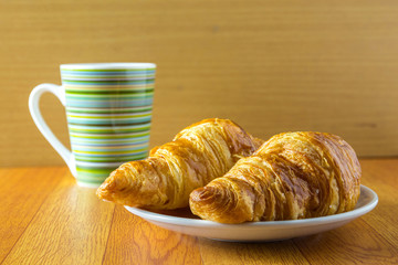 Croissant and a cup of coffee on wood table