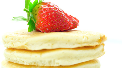 Stack of pancakes with strawberry on top, macro closeup.