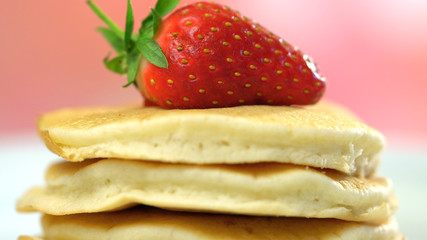 Stack of pancakes with strawberry on top, macro closeup.