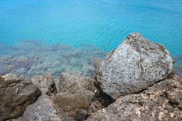 Fototapeta na wymiar Rocks of a breakwater on Mediterranean Sea beach in Kissamos town on the Crete Island, Greece