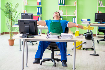 Handsome man cleaning office with vacuum cleaner
