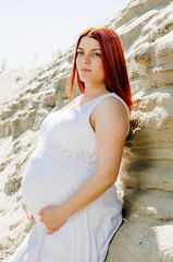 photo shoot of a pregnant couple on the beach. the girl has red hair