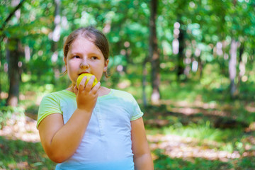 Little girl portrait eating apple outdoor apple a summer day