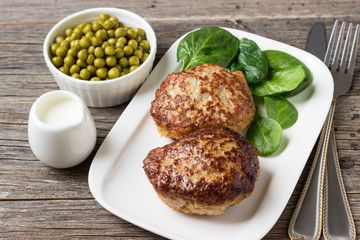 Homemade cutlets   with green peas on a plate in a rustic style.