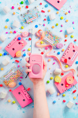 Candy cassette tapes and pink retro radio player in a hand. Candies, sprinkles and marmalades in a...