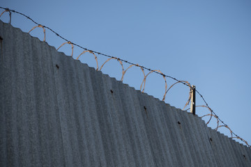 Secure wall with barbed wire fence above