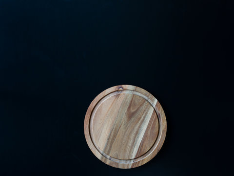 Round wood cutting board on the black background. Copy-space for your text. Top view. Flat layot