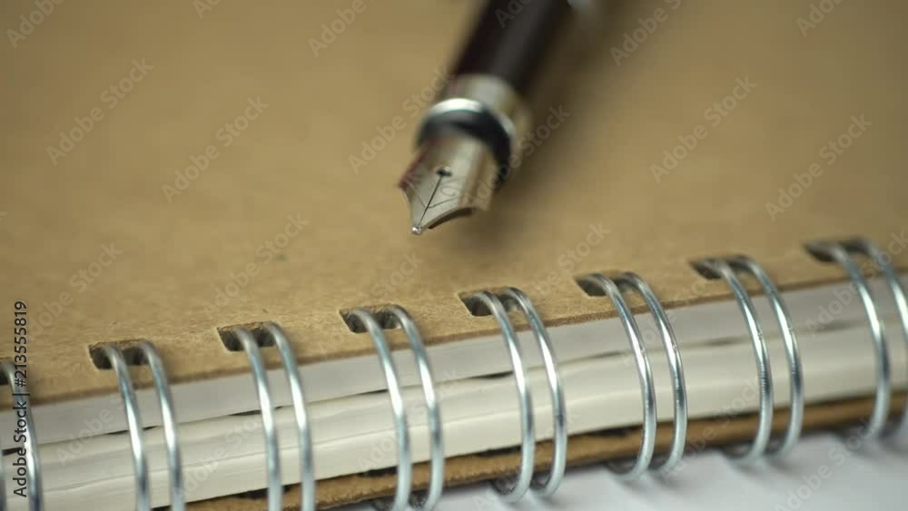 Poster expensive pen on notebook with a sliding camera move. 4k stock footage.
