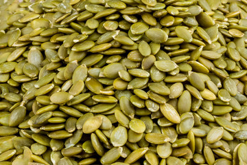 Peeled pumpkin seeds on wooden background