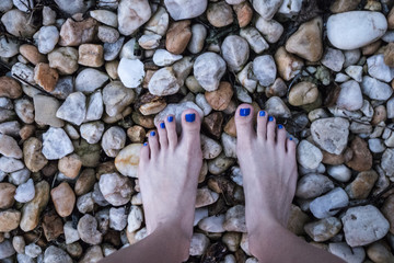 woman's bare feet on a rocky road or beach