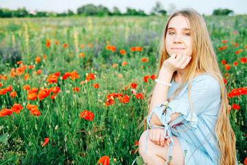 Calm happy blond woman in the field of poppy flowers