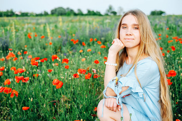 Calm happy blond woman in the field of poppy flowers