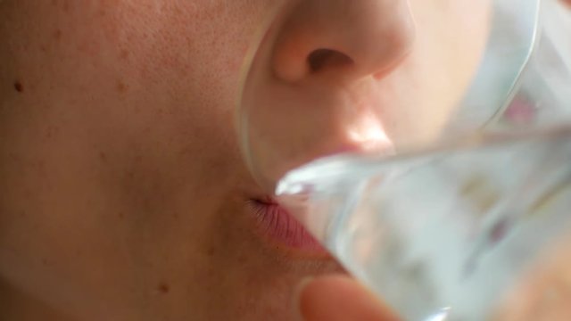 A woman puts a pill in his mouth and drinks it with water, close-up