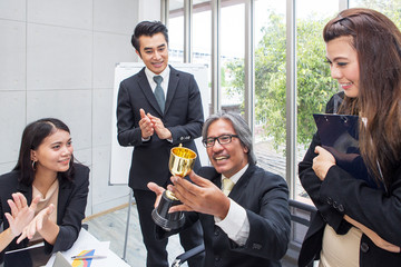 Business team winning trophy in the office. Businessman with teamwork in award and successful...