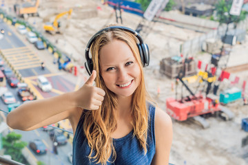 A young woman by the window annoyed by the building works outside, wired soundproof wireless...