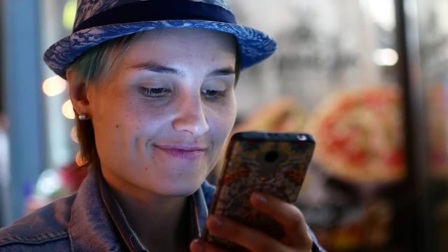 Attractive Woman using Mobile Phone During Walk on Streets of Night Town.