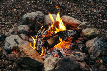 Evening small fire made of birch logs ennobled with stones. Warm hearth.
