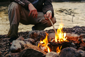 A man sitting near the campfire and enjoy the atmosphere.