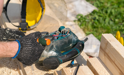 carpenter repairs woodworking tools on the street on lumber