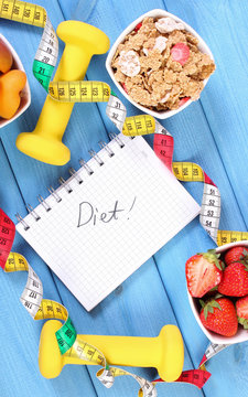Healthy food, dumbbells, centimeter and notebook for notes, concept of slimming and sporty lifestyles