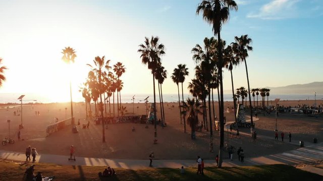 Venice Beach Drone in Los Angeles, CA with beautiful sunshine during summer next to The Pier on the Beachfront with Skaters skating in the park