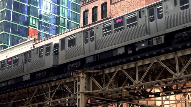 Chicago L passing through downtown loop past a red brick building.