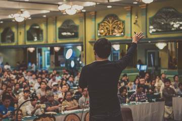 Rear view of Asian Speaker with casual suit standing and giving the knowledge over the photo...