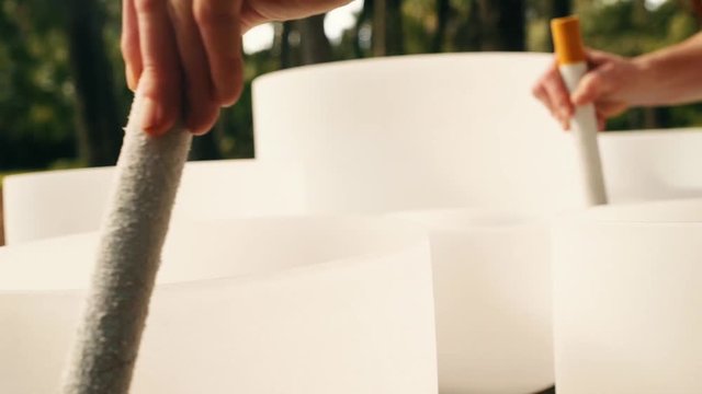 A woman's hands playing two crystal bowls at the same time in golden morning light shot on a slider moving to the right shot in slow motion.