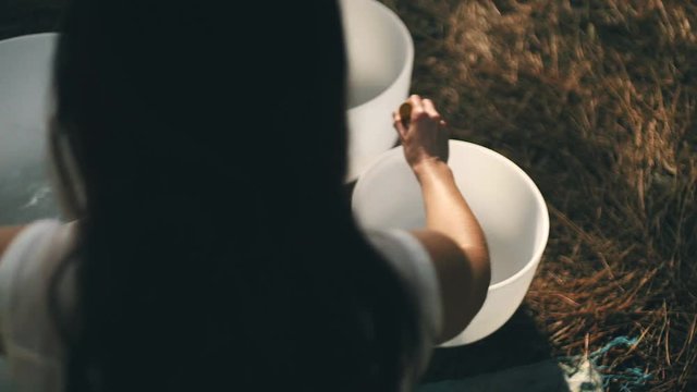 Over the shoulder perspective of woman playing Tibetan singing bowl