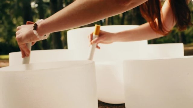 A woman's hands playing two crystal bowls at the same time in golden morning light shot on a slider moving to the left shot in slow motion.