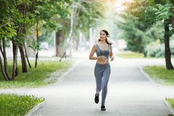 Fototapeta na wymiar Young woman jogging down a path in a green park.