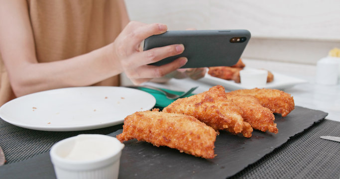Woman taking photo on fried chicken wing