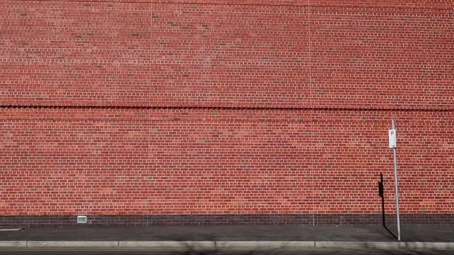 Generic brick wall with occasional car driving past