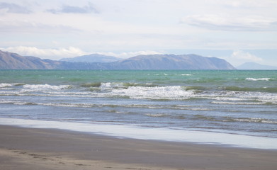 Fototapeta na wymiar Waves coming in on Raumati Beach looking out towards Pukerua Bay and Porirua on the lower west coast of the North Island of New Zealand.