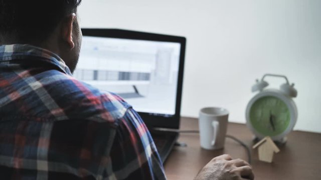 Back view of male architect  working at home on laptop, Designer sketching drawing draft working Sketch design house construction Project..