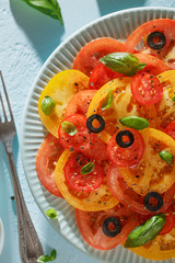 Homemade vegetable tomato carpaccio on blue plate with fork on blue background.