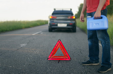 Driver standing with empty fuel canister against car background. Finished fuel. Not enough gasoline.