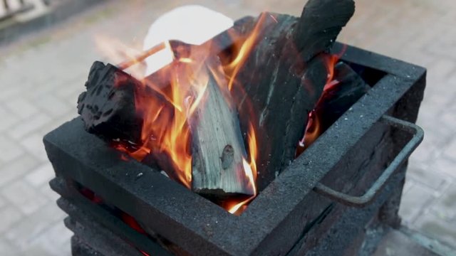 Medium shot of wood burning in a Bar B Q