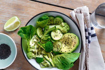 Bowl summer green salad with glass water top view